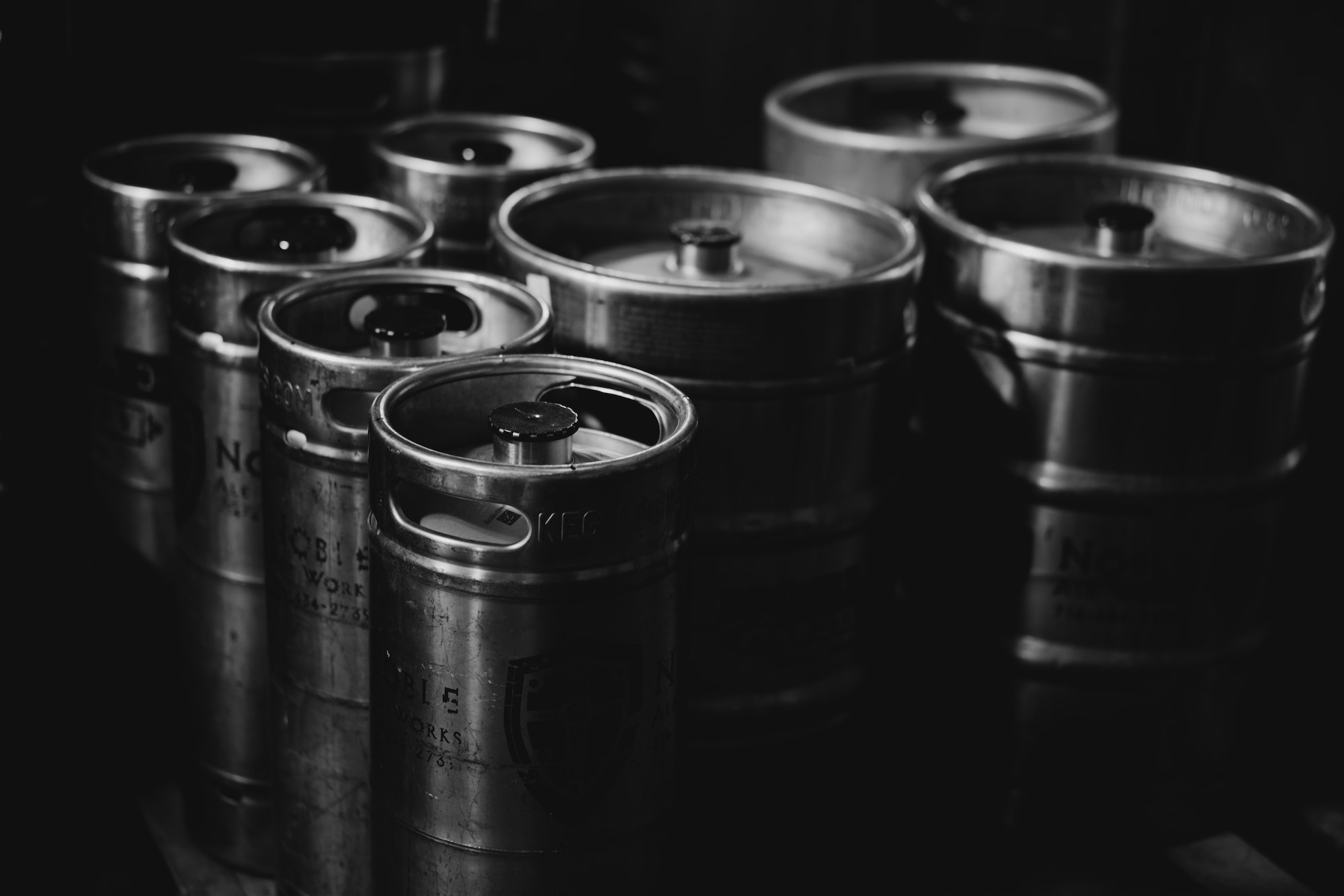 Black and white group of beer alcohol cider kombucha metal kegs at brewery warehouse industrial